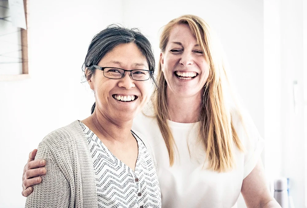 Zwei Mitglieder des goldbutt-Teams haben Spaß bei der Arbeit und lachen in die Kamera.